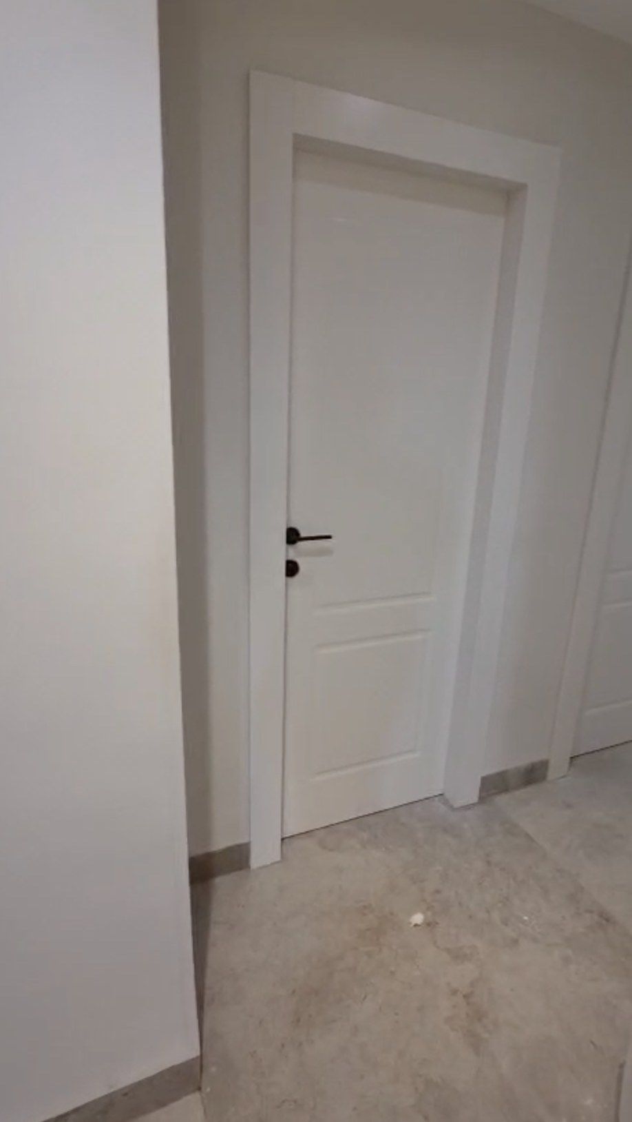 Porte intérieure blanche à moulures avec poignée noire, dans un couloir